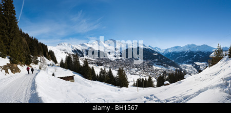 Couple en train de marcher le long d'un chemin avec une vue panoramique sur la station de Verbier, Valais, Suisse Banque D'Images