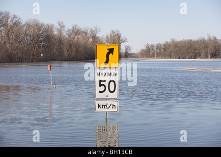 Signe de route sur route qui est couvert avec l'eau de l'inondation de la rivière Rouge, Manitoba, Canada Banque D'Images