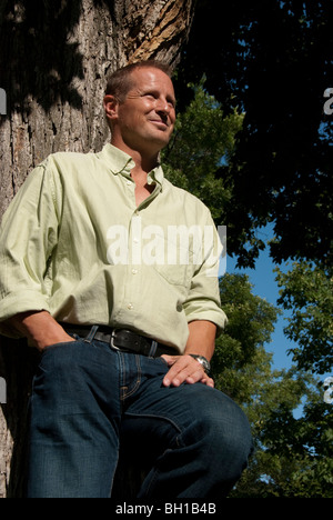 Low angle view of Man in '40 leaning against tree, Parc Assiniboine, Winnipeg, Manitoba, Canada Banque D'Images