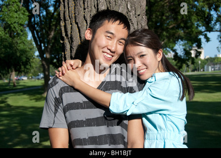 Jeune couple se placer à côté de l'arbre dans le parc Assiniboine, Winnipeg, Manitoba, Canada Banque D'Images