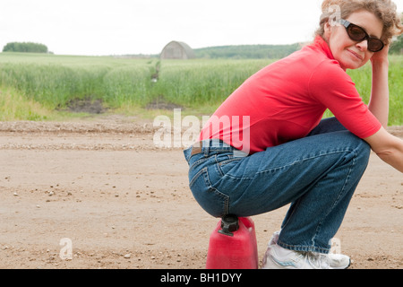 Femme assise sur bidon, couvertes de route rurale, Manitoba, Canada Banque D'Images