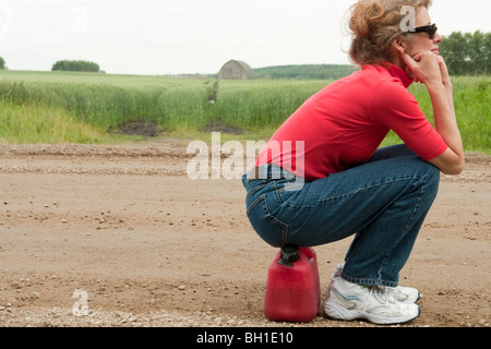 Femme assise sur bidon, couvertes de route rurale, Manitoba, Canada Banque D'Images