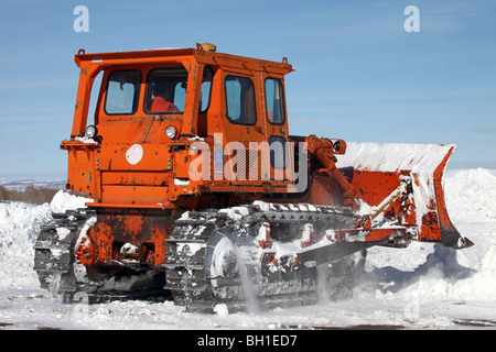 Caterpillar bulldozer poussant la neige profonde au large de route de montagne dans le centre de l'Utah. Véhicule de couleur orange avec moteur diesel. Banque D'Images