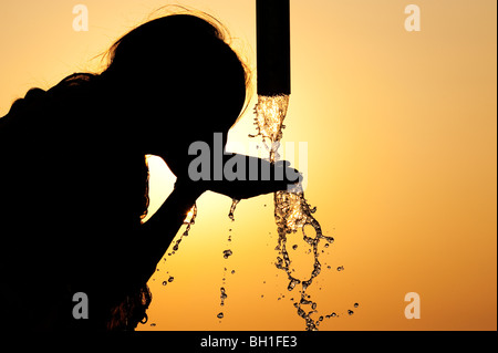 Silhouette d'une jeune indienne d'une pompe à eau potable. L'Inde Banque D'Images