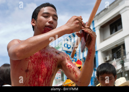 Le Festival Végétarien de Krabi, Thaïlande, implique une procession rue parfois sanglantes. Cet homme s'est coupé avec une hache. Banque D'Images