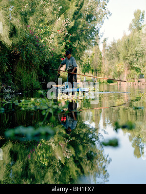 Un homme dans un bateau entre les îles de natation, Canales Embarcadero, Xochimilco, Mexique, Amérique Latine Banque D'Images