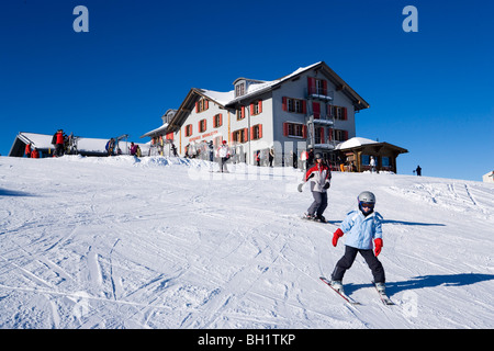 Skieurs sur pente, alpine lodge Maennlichen en arrière-plan, Maennlichen, Grindelwald, Oberland Bernois, Canton de Berne, Suisse Banque D'Images