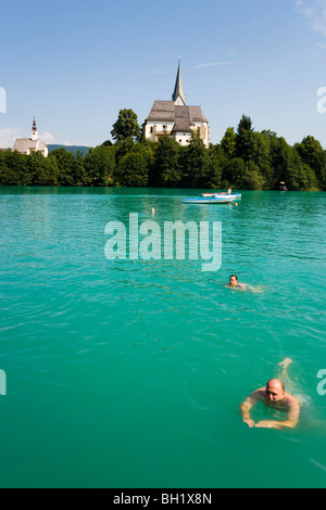 La natation de personnes dans le Wörthersee (plus grand lac de Carinthie), Église Paroissiale et Rosaire église en arrière-plan, Maria Woerth, location Banque D'Images