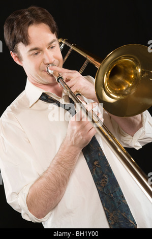 Mid-adult man with open-collar shirt joue du trombone Banque D'Images