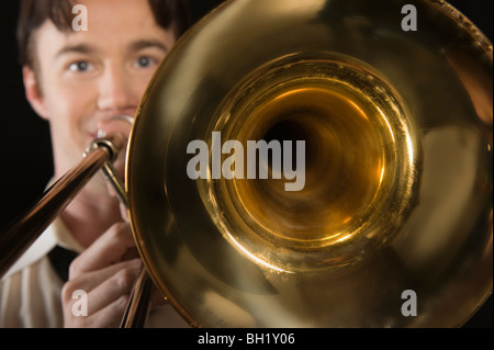 Mid-adult man with open-collar shirt joue du trombone Banque D'Images