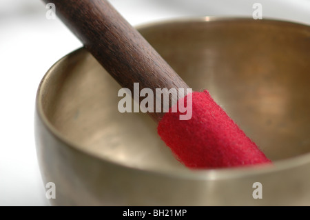 Un gros plan d'un brassTibetan bol chantant avec un manche en bois et feutre rouge Banque D'Images
