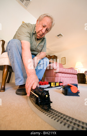 Un homme âgé à la retraite et son jouet train miniature. Banque D'Images