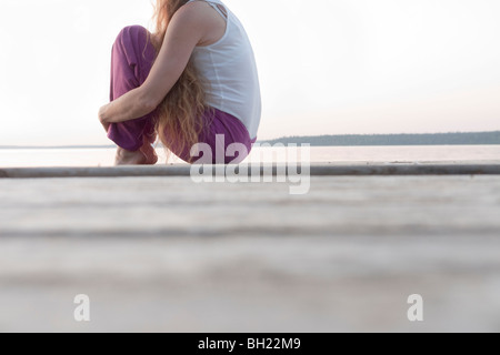 Femme assise sur un quai par Clear Lake, Manitoba, Canada Banque D'Images