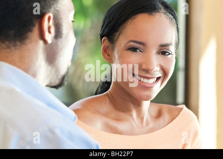 Une happy African American man and woman couple assis à l'extérieur de la femme aussi souriant pour appareil photo. Banque D'Images
