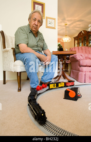 Un homme âgé à la retraite et son jouet train miniature. Banque D'Images