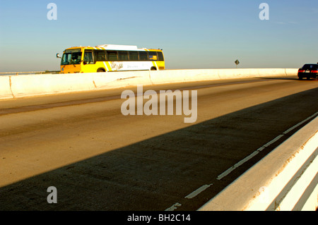 Gros camions et autobus rugir sur un pont de la ville crachant Co2 et autres polluants dans l'air rempli de smog. Banque D'Images