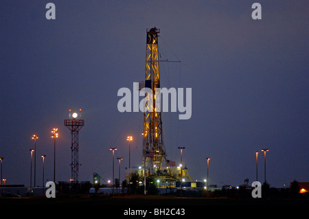 Forage pétrolier sur la propriété publique domine les structures environnantes à l'Aéroport International de Dallas au crépuscule. Banque D'Images