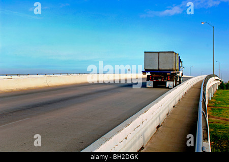 Gros camions et autobus rugir sur un pont de la ville crachant Co2 et autres polluants dans l'air rempli de smog. Banque D'Images