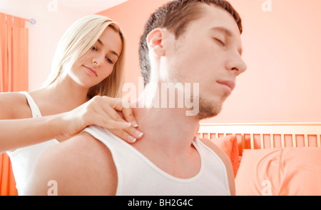 L'homme et la femme s'asseoir sur le lit de massage des épaules de l'homme femme. Format horizontal. Banque D'Images