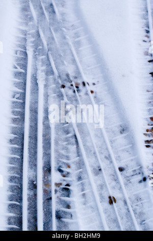 Pneu de voiture imprime en adoucissant la fonte de la neige sur une route de gravier. Banque D'Images