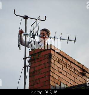 Un ingénieur de la télévision numérique l'installation d'un nouveau téléviseur compatible sur antenne à une cheminée d'une maison Banque D'Images