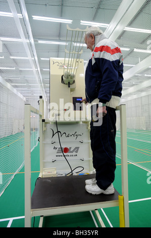 L'entraîneur de cricket de Sussex en utilisant Merlyn par BOLA bowling spin machine dans la pratique à l'école à l'intérieur de filets Banque D'Images