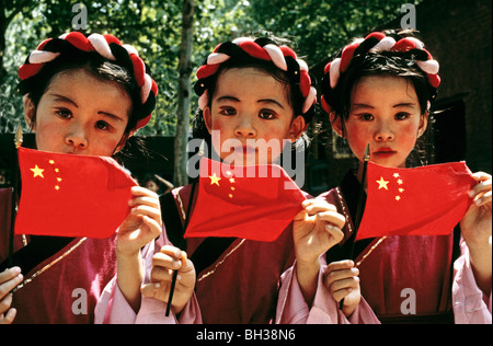 Les enfants Chinois Han de la Chine avec les drapeaux nationaux à Jinan habillés en vêtements traditionnels des Miao Nationalité ethnique Banque D'Images