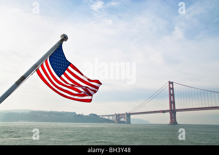 Brandissant le drapeau américain dans la gloire avec le Golden Gate Bridge en arrière-plan. Banque D'Images