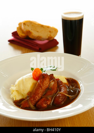 Saucisses et purée à l'oignon de la sauce, du pain et une pinte de Guinness. Banque D'Images