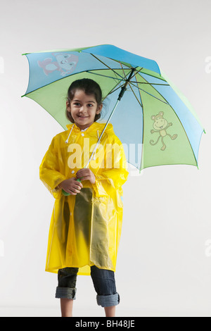 Jeune fille portant un imperméable et tenant un parapluie Banque D'Images