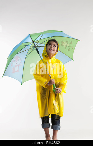 Jeune fille portant un imperméable et tenant un parapluie Banque D'Images