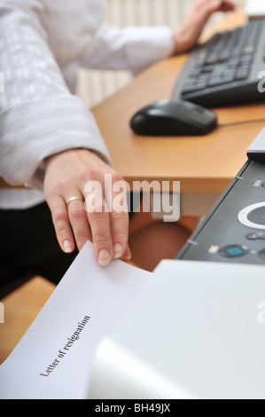 Main de femme reching d'affaires papier (lettre de démission écrite sur le lieu de travail de l'imprimante) Banque D'Images