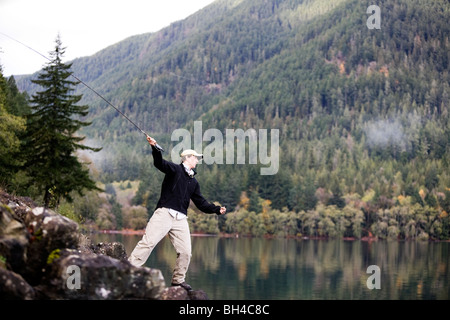 Un homme poissons mouche Lake Crescent à Washington's Olympic National Park. Banque D'Images