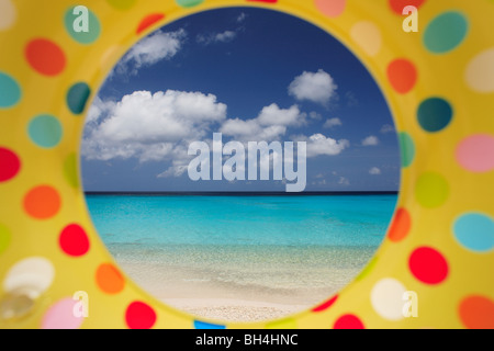 Une plage tropicale vue à travers le trou dans un anneau en caoutchouc gonflables aux couleurs vives (paysage) Banque D'Images