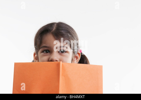 Girl couvre la moitié de son visage avec un livre Banque D'Images