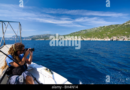 Photographe sur un bateau dans la plage de Cala Luna, Sardaigne, île de l'Italie. Eau bleu clair dans la baie de Cala Luna, Mer Méditerranée. Banque D'Images