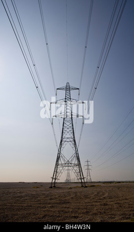 Les pylônes d'électricité provenant de la centrale nucléaire de Dungeness plant uk au coucher du soleil Banque D'Images