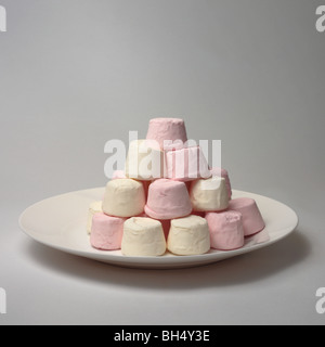 Les guimauves rose et blanc empilés sur une assiette Banque D'Images
