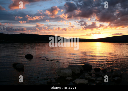 Coucher de soleil sur un rivage rocailleux du Loch Lomond. Banque D'Images