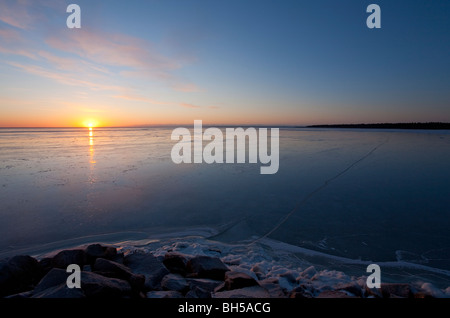 Derniers rayons de soleil se reflétant de la nouvelle couche immaculée de glace de mer au coucher du soleil, Finlande Banque D'Images