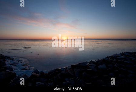 Derniers rayons de soleil se reflétant de la nouvelle couche immaculée de glace de mer au coucher du soleil, Finlande Banque D'Images