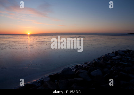 Derniers rayons de soleil se reflétant de la nouvelle couche immaculée de glace de mer au coucher du soleil, Finlande Banque D'Images