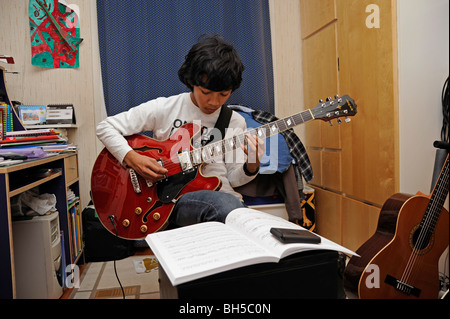 Garçon jouer avec une guitare jazz Aria, style Gibson 335 Banque D'Images