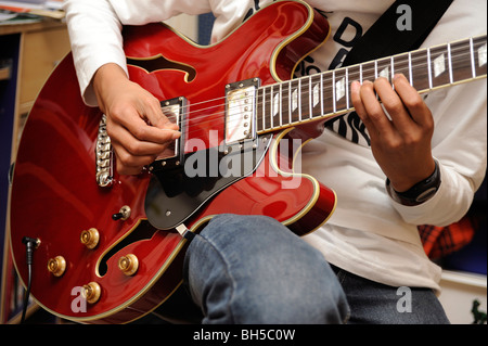 Garçon jouer avec une guitare jazz Aria, style Gibson 335 Banque D'Images