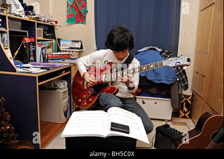 Garçon jouer avec une guitare jazz Aria, style Gibson 335 Banque D'Images