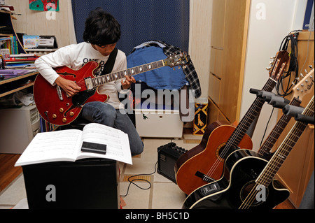 Garçon jouer avec une guitare jazz Aria, style Gibson 335 Banque D'Images