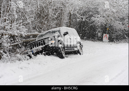 Une voiture se trouve dans un fossé après avoir perdu le contrôle le contrôle lors de conditions routières glaciales. Banque D'Images