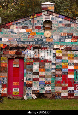 Mur de plaques d'immatriculation voiture métal sur garage avec porte rouge Banque D'Images