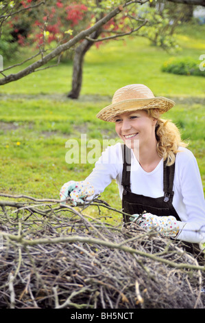 Young woman cleaning arbre membres in orchard Banque D'Images