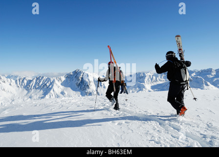 Deux skieurs randonnée portant leurs skis sur terrain hors-piste, Gemsstock, Andermatt, Suisse Banque D'Images